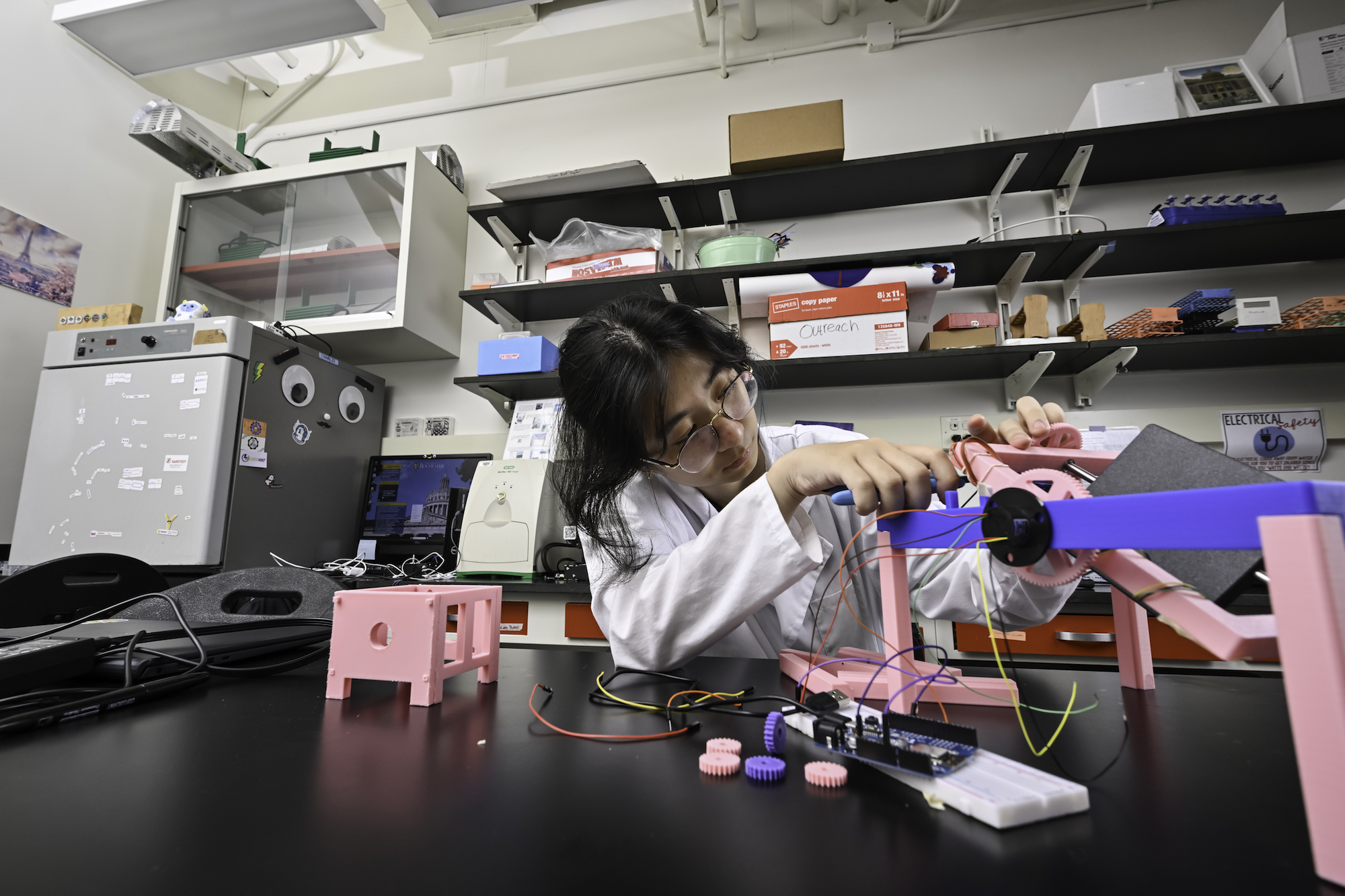 Cell and developmental biology major Jessica Wang ’28 removes plastic scraps from a 3D-printed gear on a device the team engineered called a clinostat.