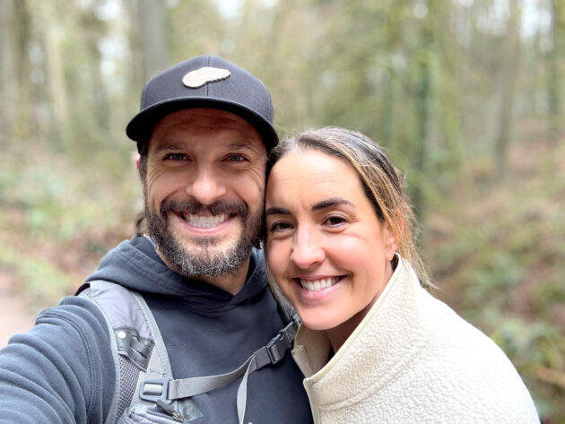 Kevin Demoskoff and his wife Rachelle smile together with trees in the background.