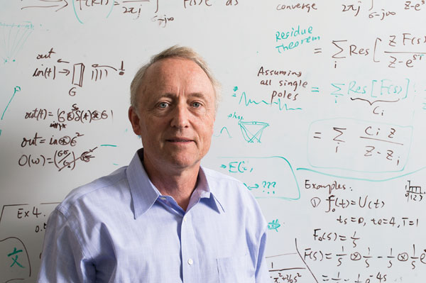 Kevin J. Parker, a professor at the University of Rochester, stands in front of a whiteboard in his lab.