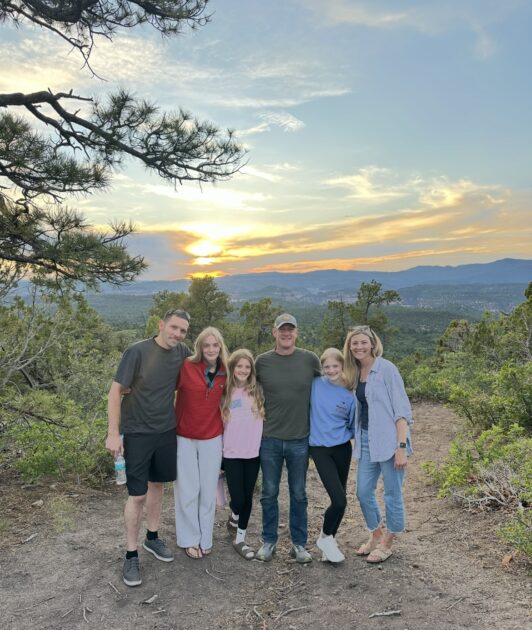 Jess Delaney-Sloper and her family smile together on a scenic overlook in Zion National Park.