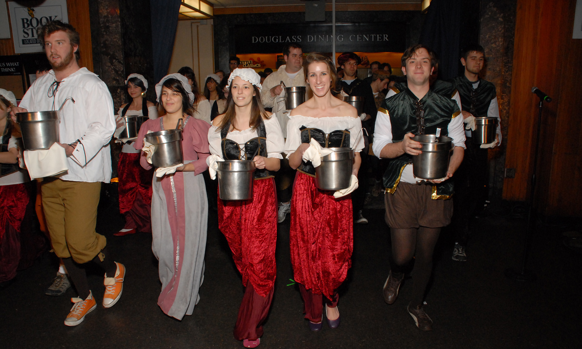 Group of University of Rochester undergraduates promenading in medieval garb and holding giant tankards.