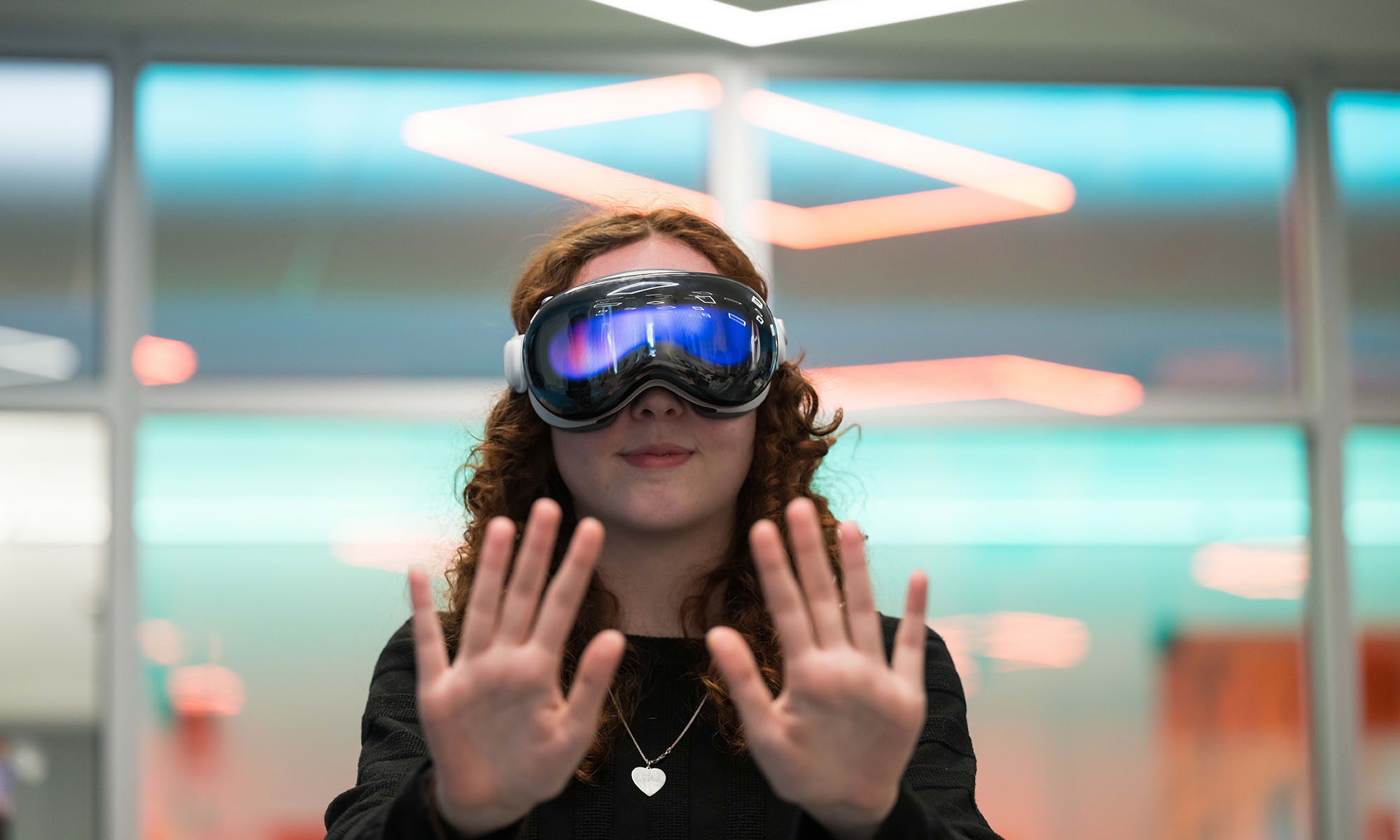A University of Rochester student wears AR/VR glasses and holds her hands in front of her while interacting with the system.