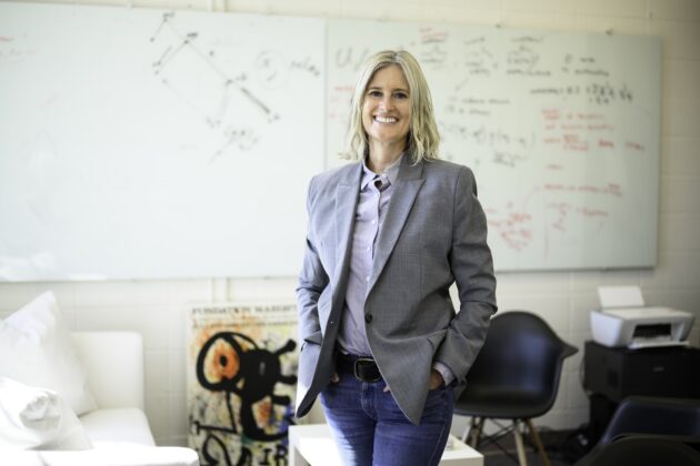 Political science professor Gretchen Helmke stands in her office with whiteboards and notes behind her.