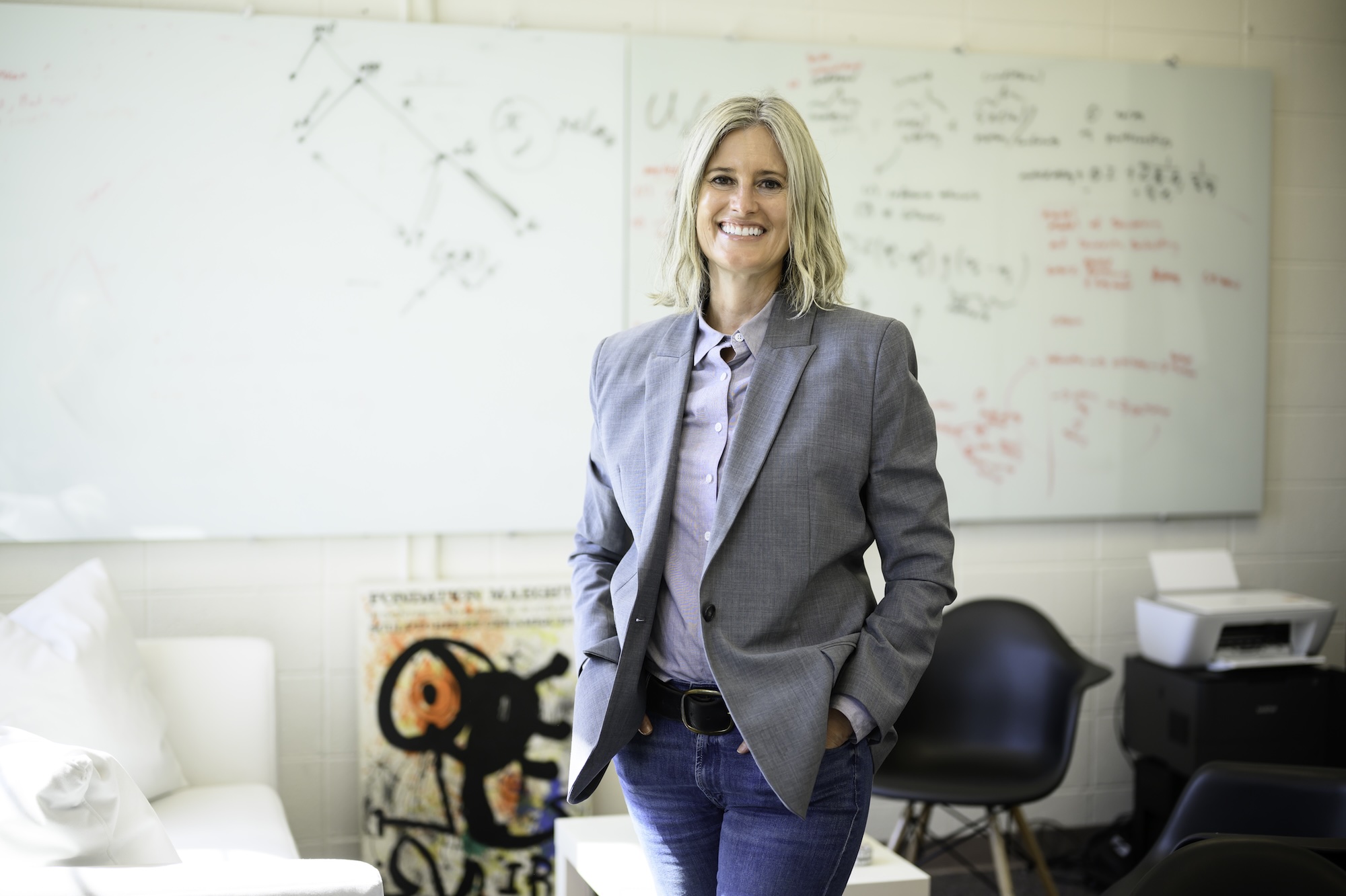 Political science professor Gretchen Helmke stands in her office with whiteboards and notes behind her.