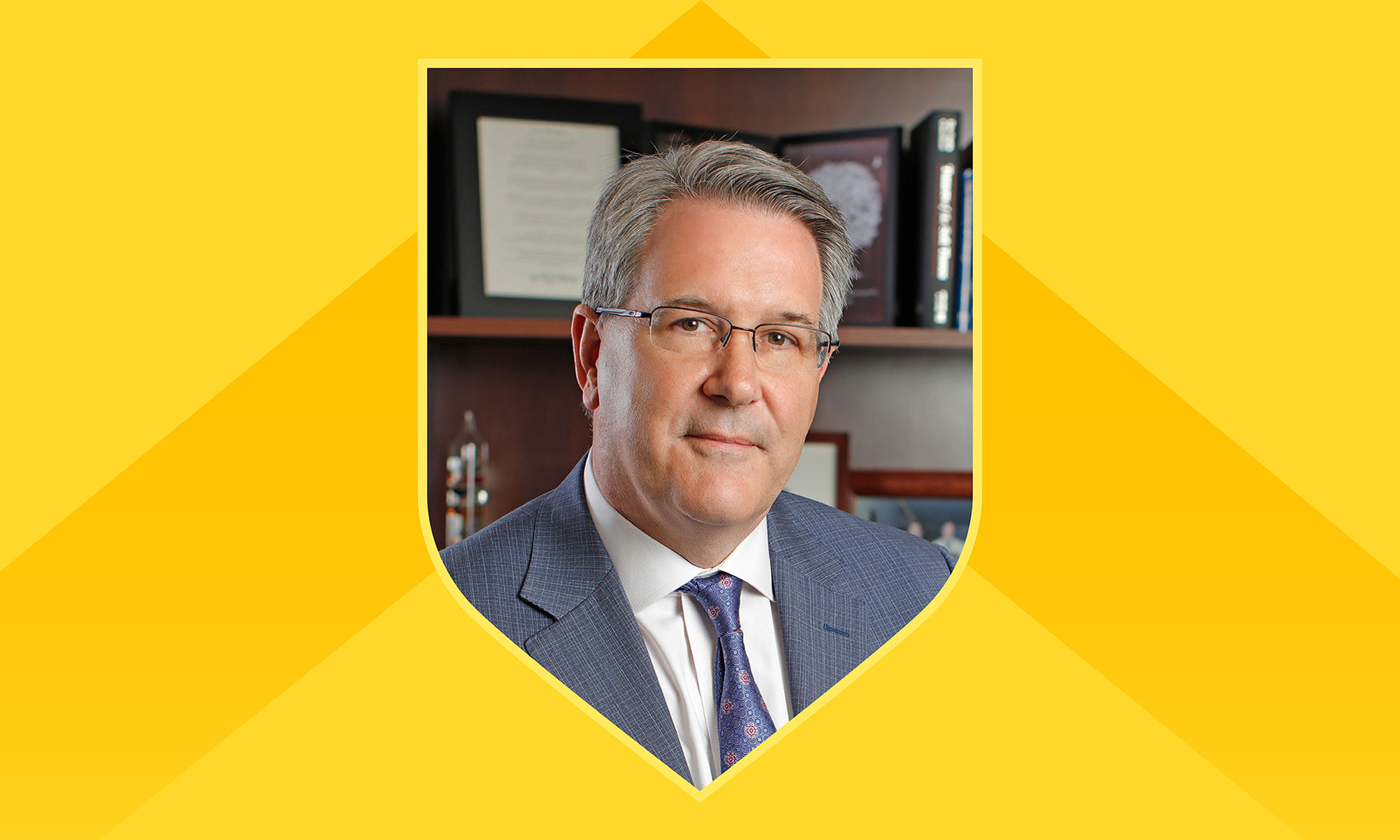 Portrait of David Linehan framed within a shield outline against a light yellow background with a darker yellow chevron incorporated.