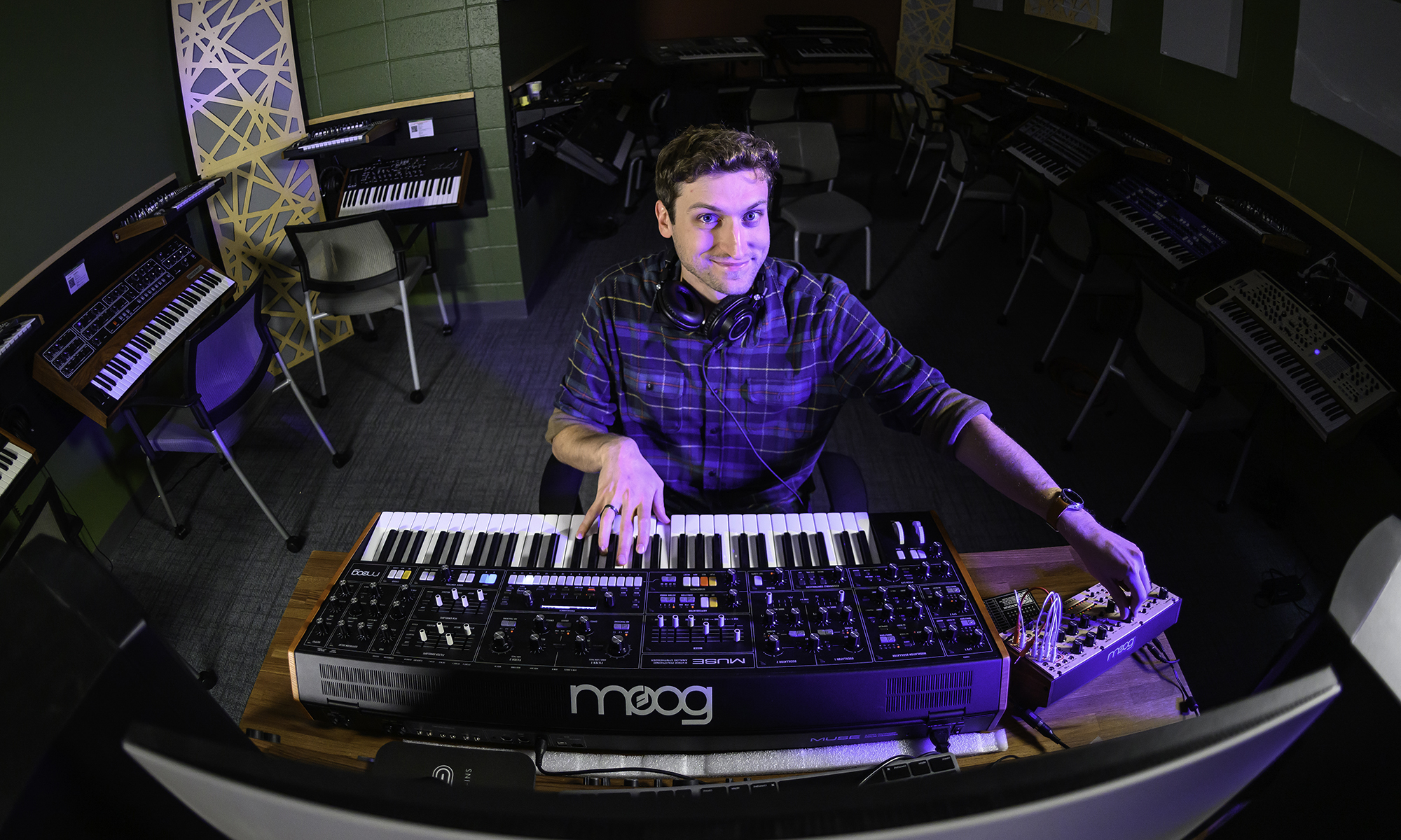 Rick Carl sitting in front of a Moog Synthesizer in the University of Rochester's synthesizer lab.