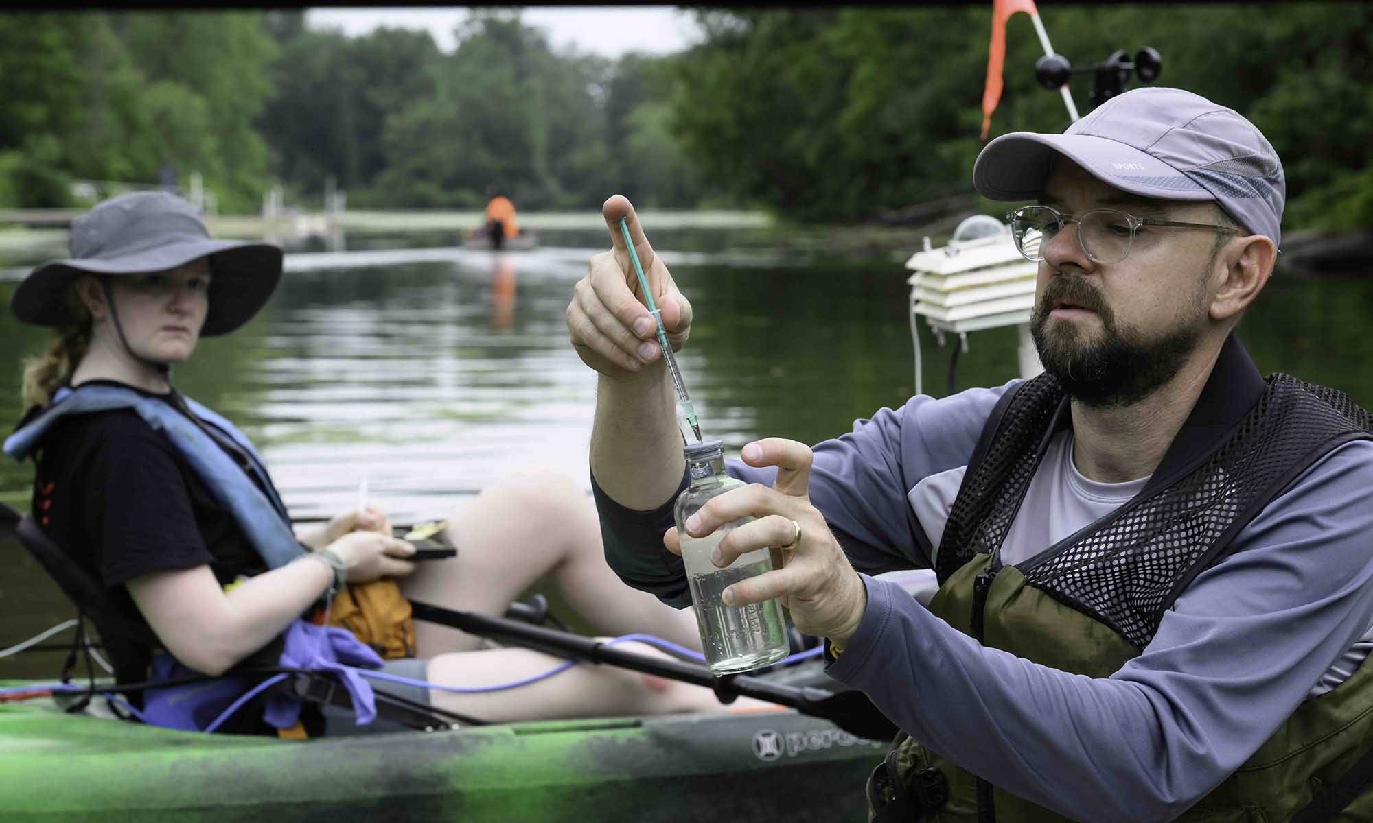 Katherine Gregory and John Kessler in specially outfitted kayaks collect and measure samples of water from the Genesee River and Erie Canal.