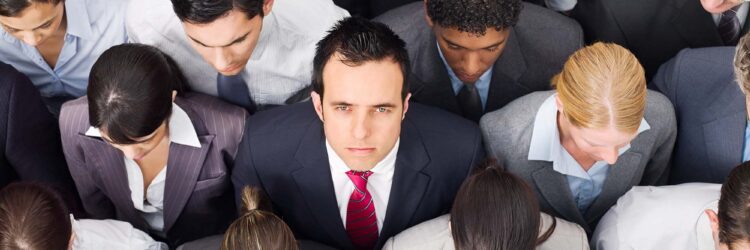 Overhead view of young business professionals tightly grouped and staring ahead, except for one man looking up in dismay to illustrate employee turnover at top firms.