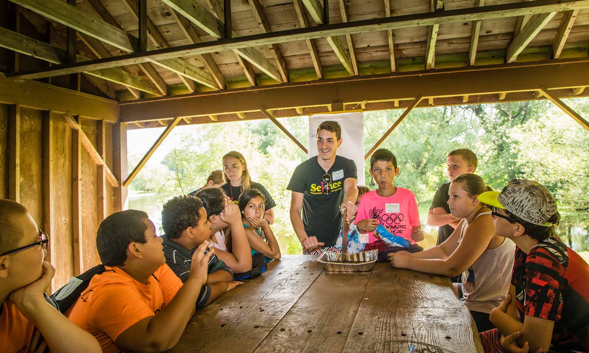 Two teacher-educators at the head of a table of students from rural schools under a park shelter.
