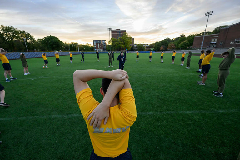 URochester NROTC midshipmen stretching in a circle in Fauver Stadium.