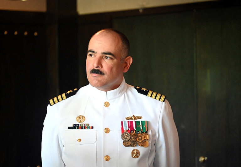 Jonathan Hopkins in his Navy uniform looks off camera for a portrait.