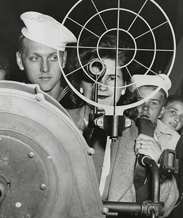 Black and white archival photo of NROTC students examining nautical equipment.