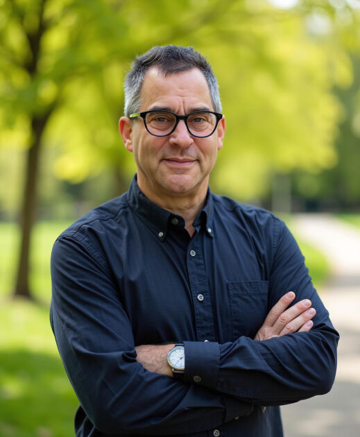 Vertical portrait of Barry Silverstein outdoors with a park and greenery in the background.