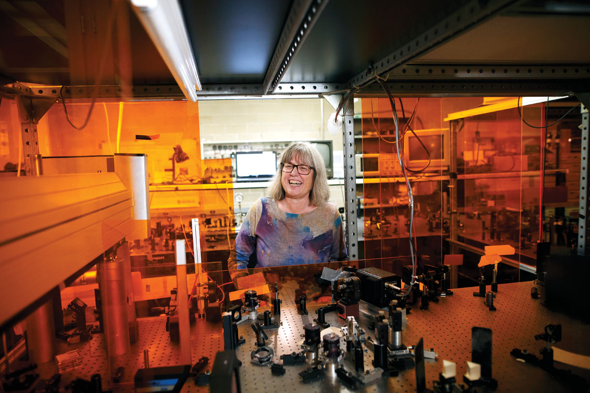 A woman stands in front of a mirror in a lab, celebrating physicist Donna Strickland's 2018 Nobel Prize win.