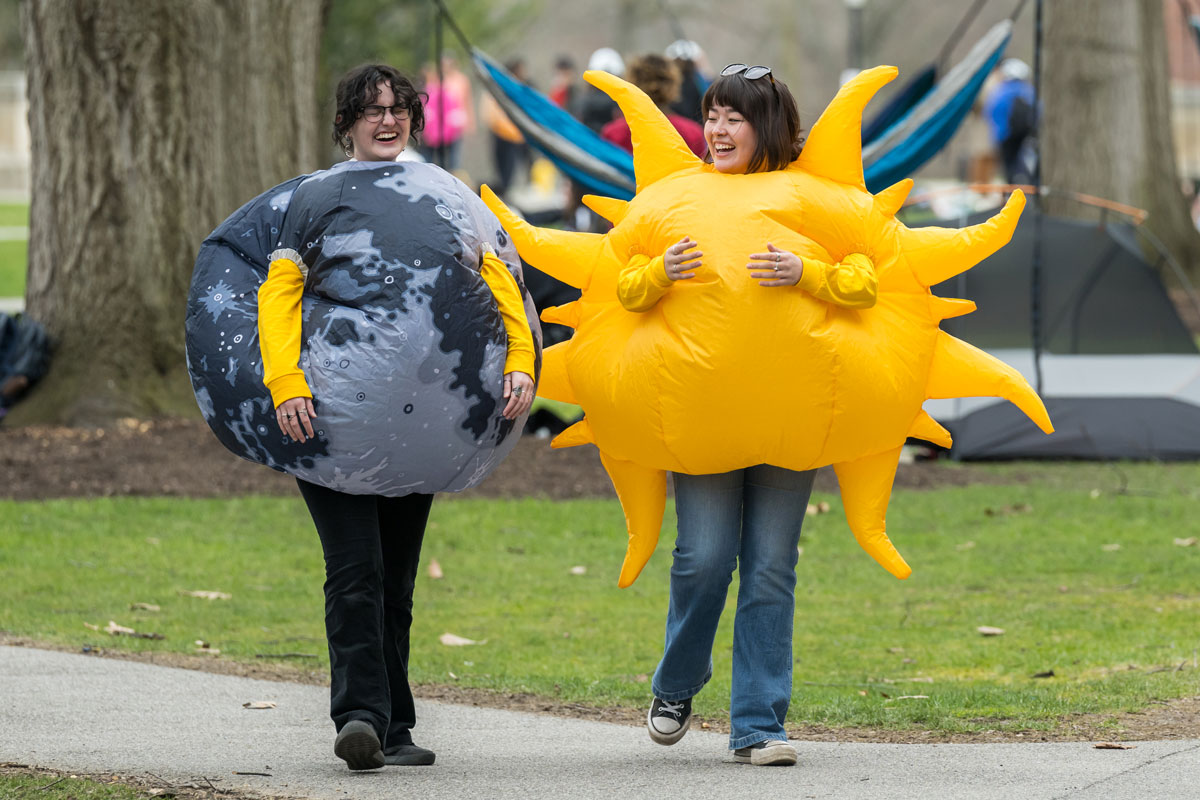 Two University of Rochester students dressed as the sun and the moon at an eclipse watch party.