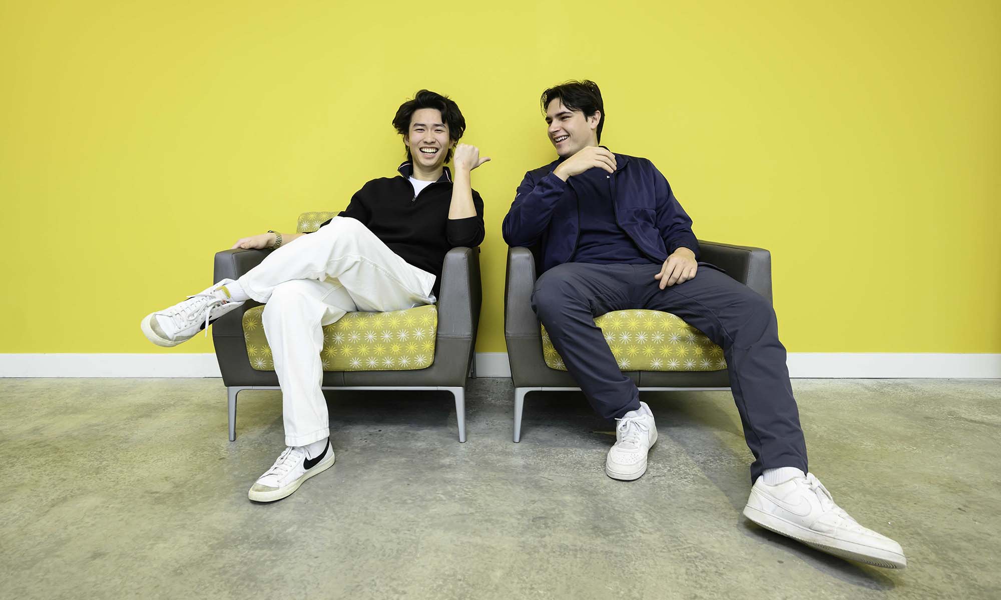 Steve Lim and Walter McDonald smile while seated in chairs against a bright yellow background.
