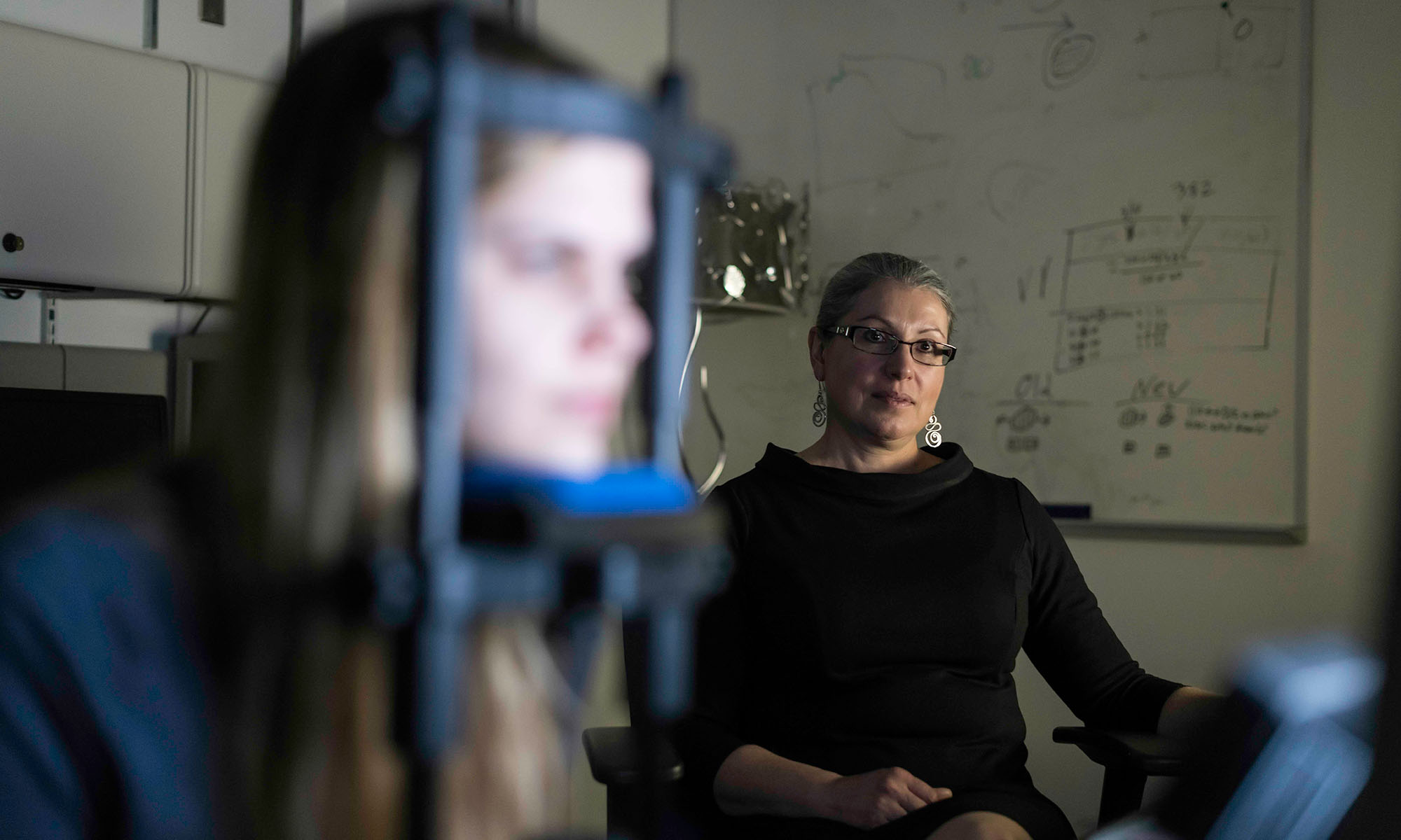 A woman in the foreground hooked up to eye-tracking equipment while vision loss researcher Krystel Huxlin looks on.