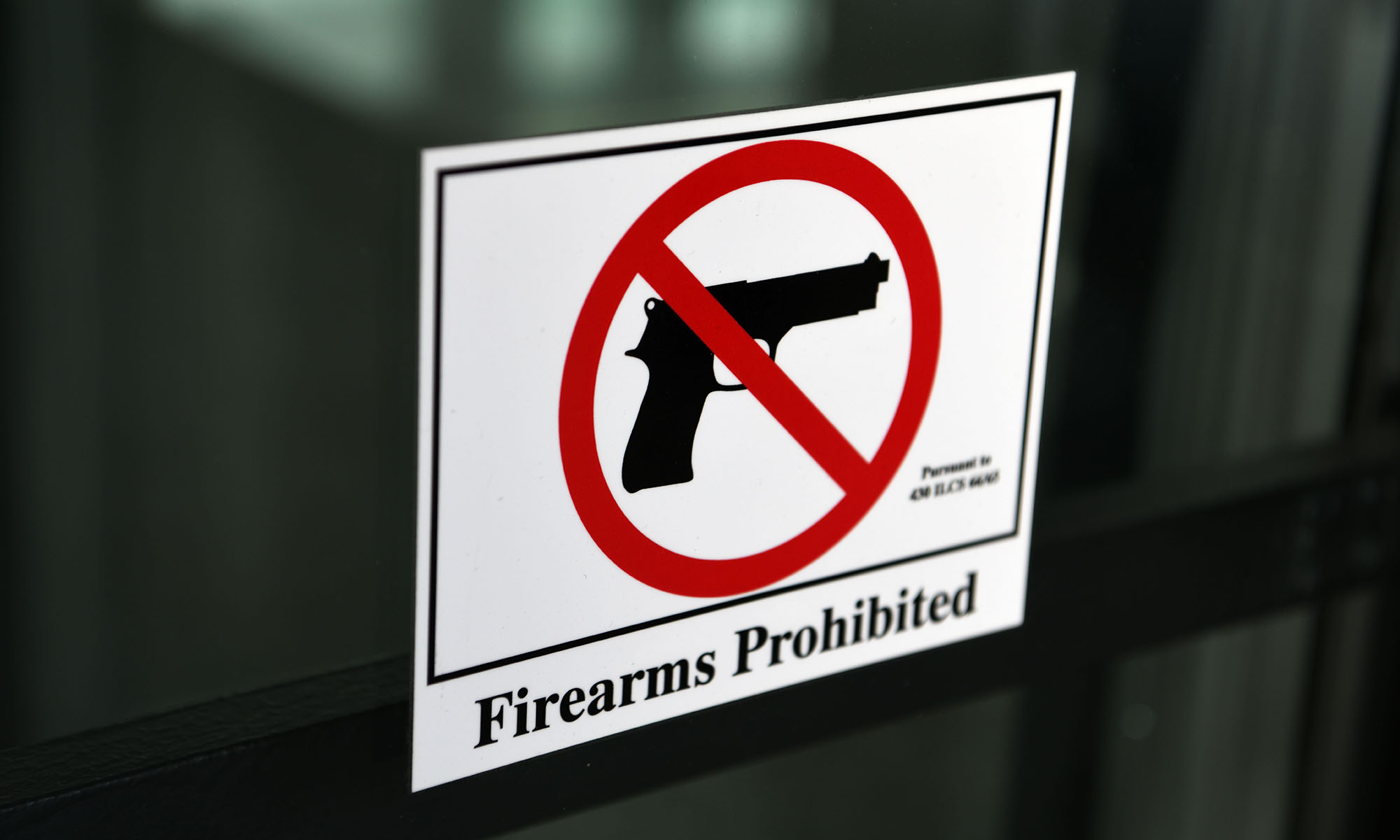 Sign on a glass door showing a NO symbol over an firearm icon with words that read "firearms prohibited", which includes gun kits (aka ghost guns), according to the Supreme Court.