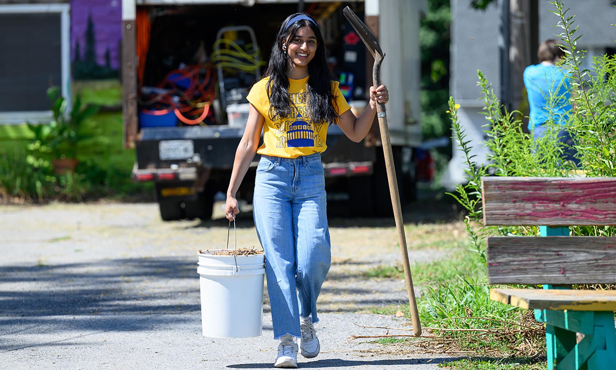 A University of Rochester student carries a bucket and shovel while smiling during a community service activity that helped result in the Carnegie Community Engagement Classification for the institution.