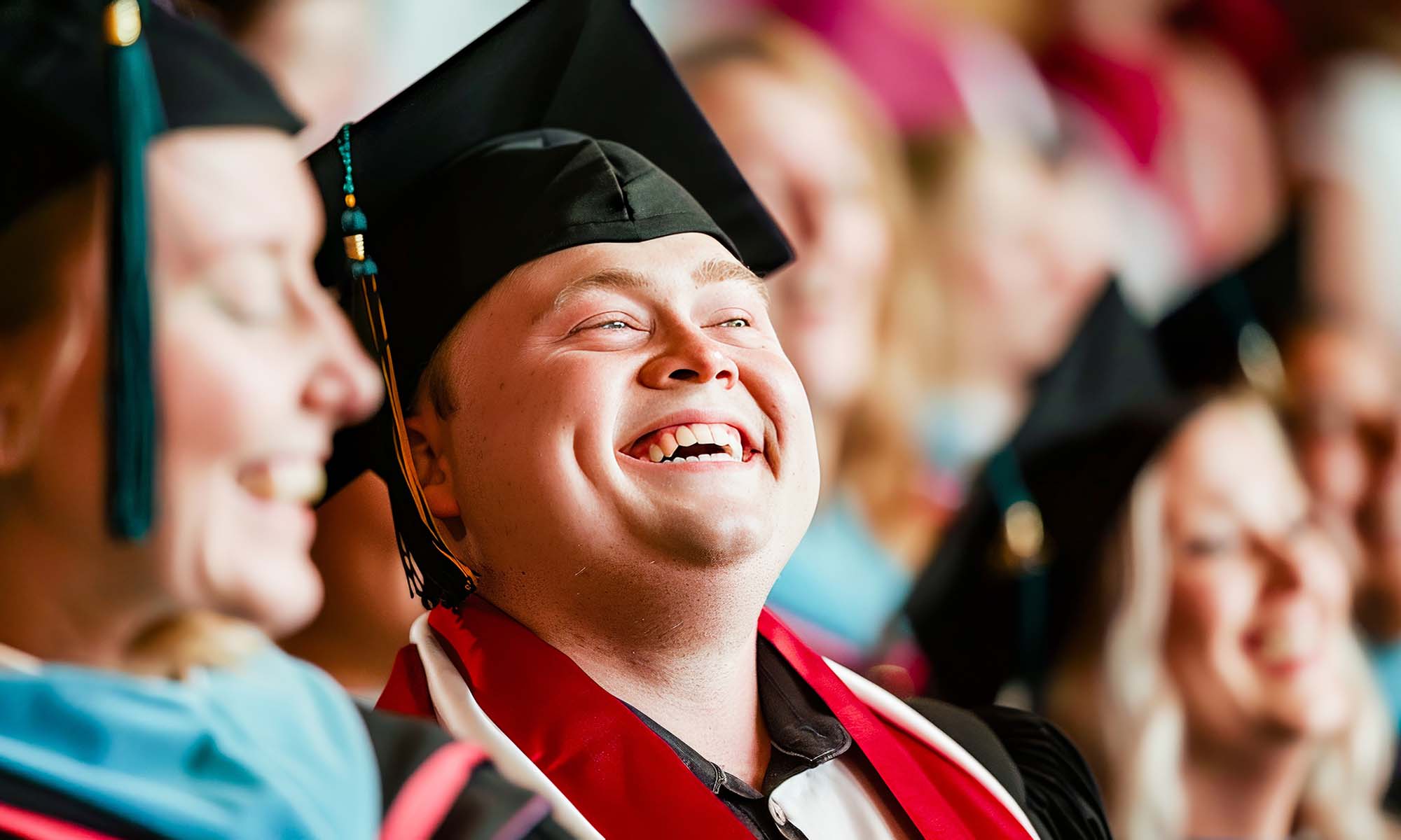 A student with intellectual disability (Down syndrome) surrounded by friends and family at graduation.