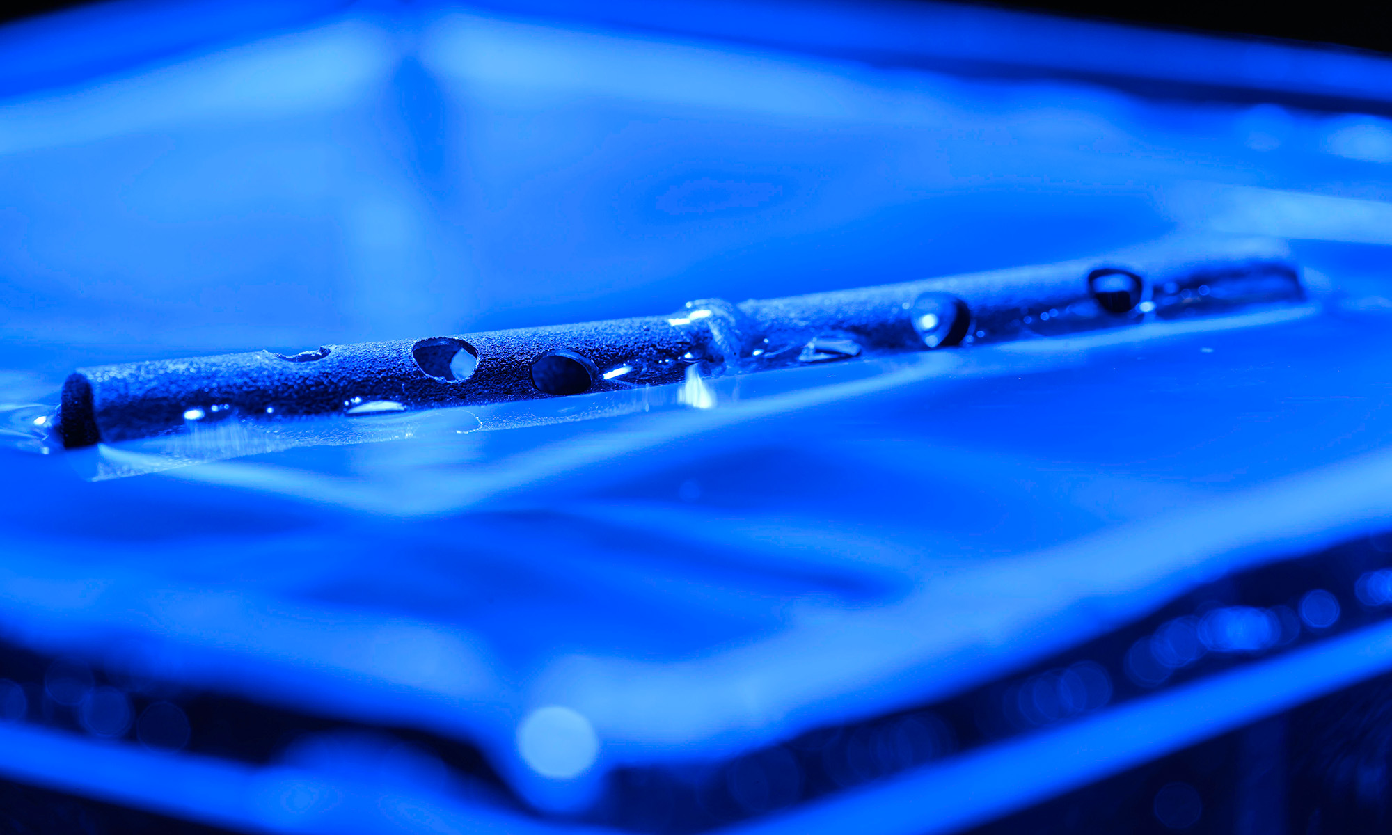 An unsinkable metal tube with holes drilled in it floats atop water.