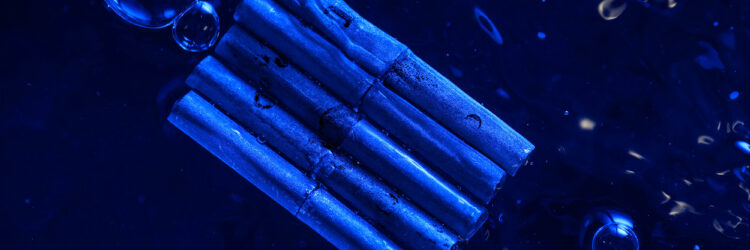 Five unsinkable metal tubes bound together and seen from above floating in water with bubbles nearby and an overall blue cast.