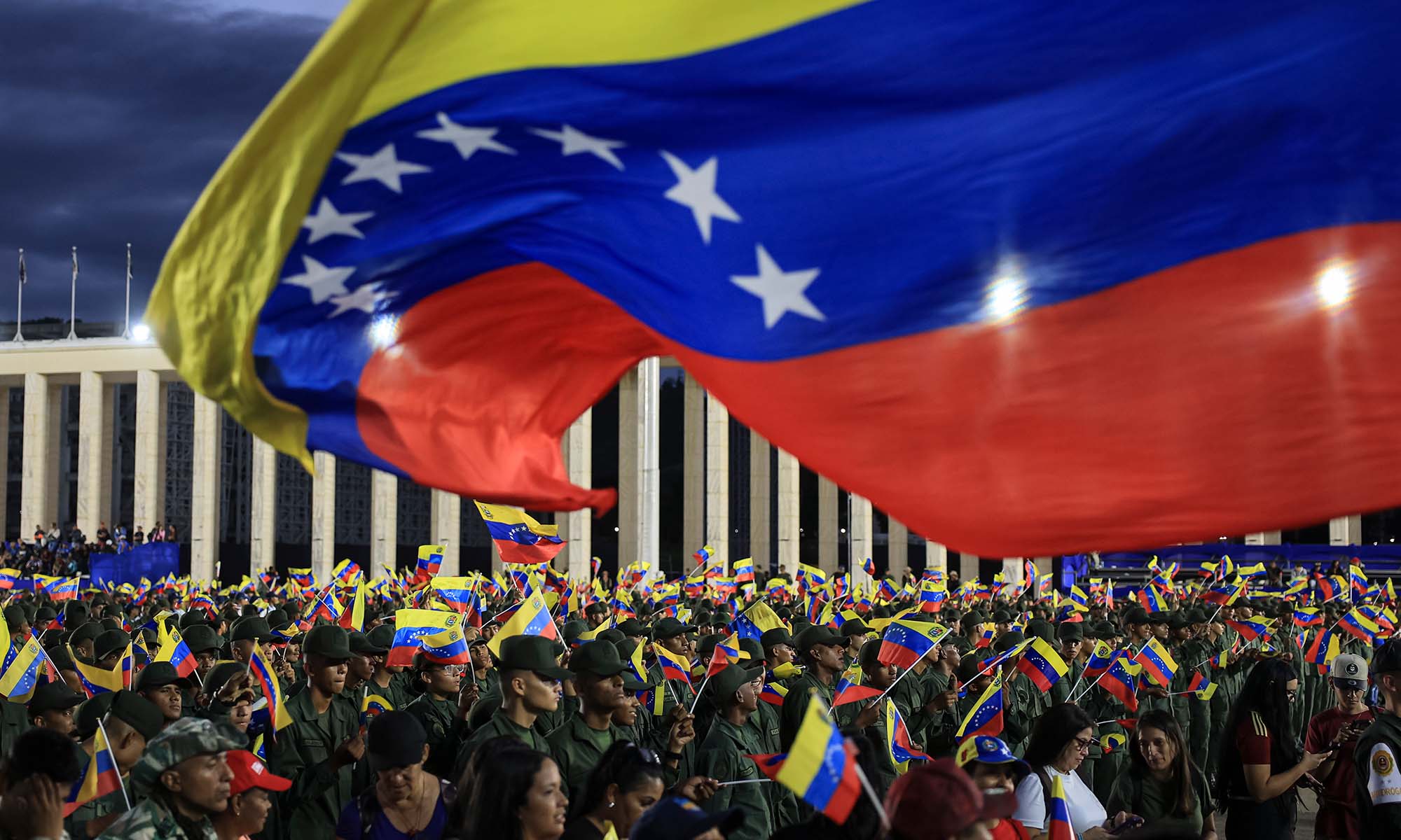 Members of the Bolivarian National Armed Forces of Venezuela wave Venezuelan flags during a military ceremony.