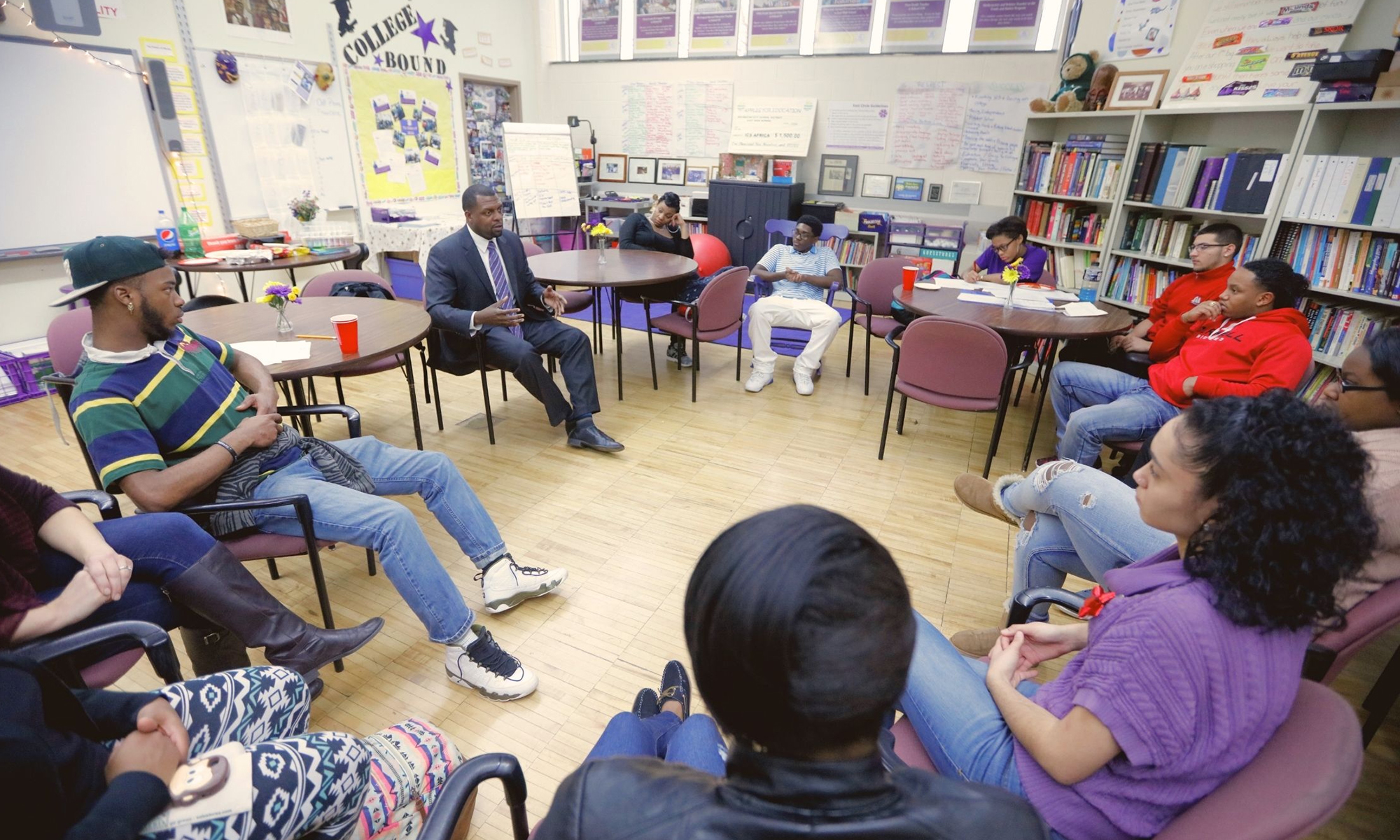 Shaun Nelms sitting in a classroom with a group of students.