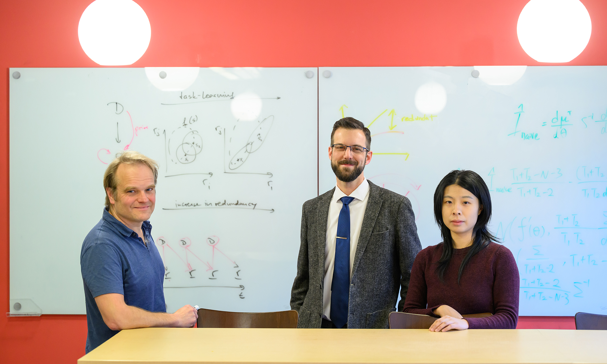 Ralf Haefner, Adam Snyder, and Shizhao Liu stand in front of a whiteboard covered in writing.