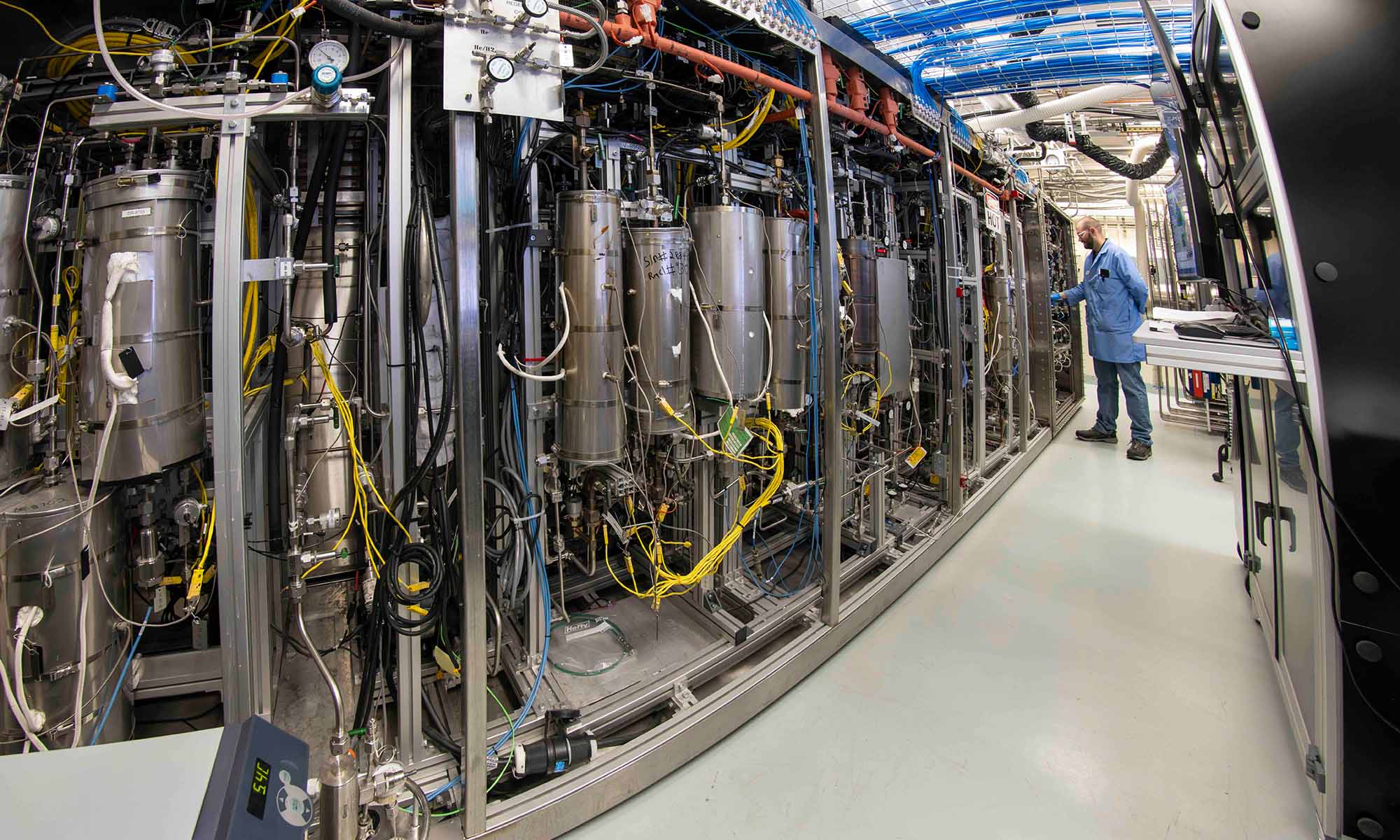A man in a blue lab coat working in the Laboratory for Laser Energetics' tritium facilities.