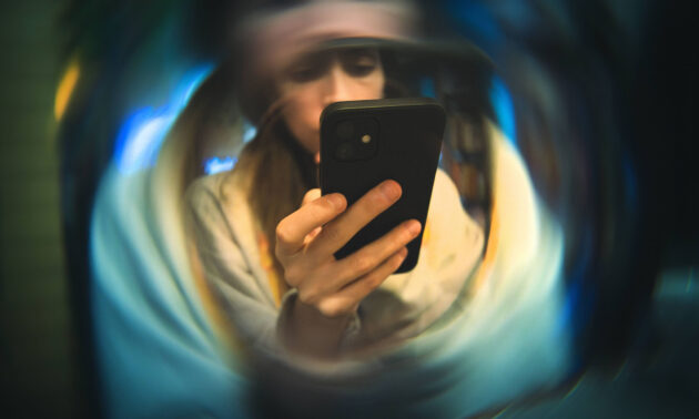 Young woman deeply engaged with her smartphone, seen through a distorted, swirling blur effect to illustrate the concept of social media echo chambers.