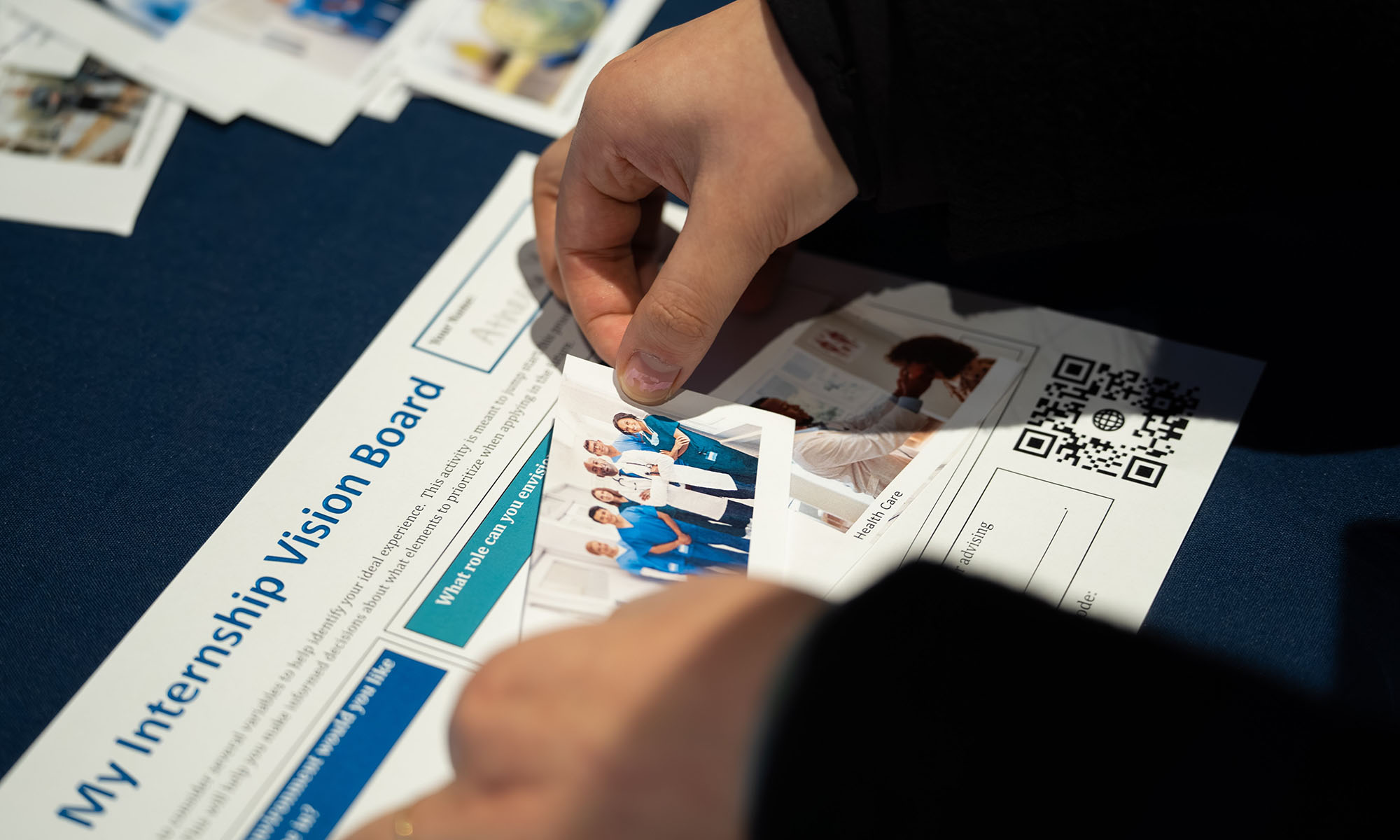 Close-up of hands affixing a photo to a sheet that reads "My Internship Vision Board."