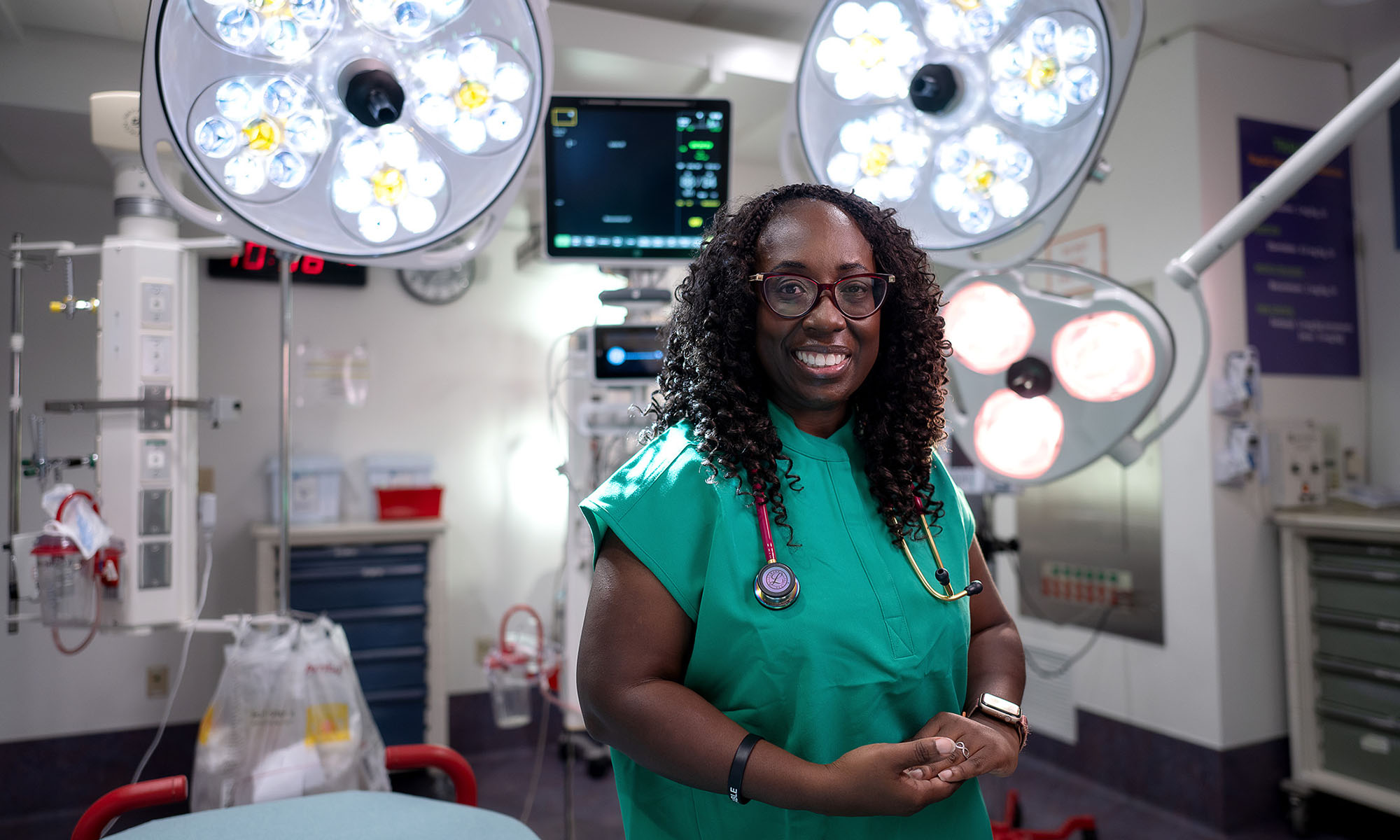 Sylvia Owusu-Ansah outfitted in medical scrubs smiling at the camera while in an emergency room.