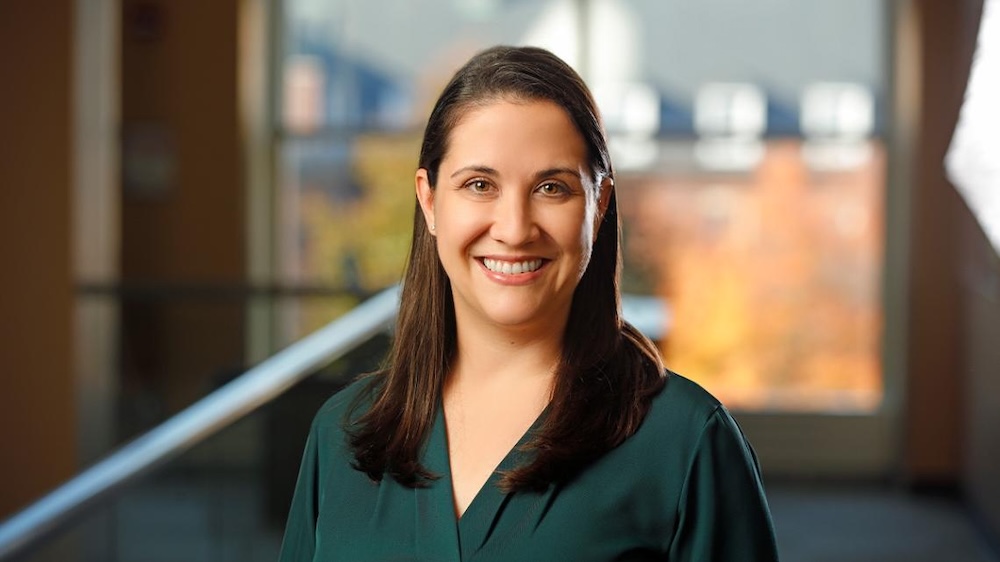 professional portrait of woman with brown hair wearing a green shirt.