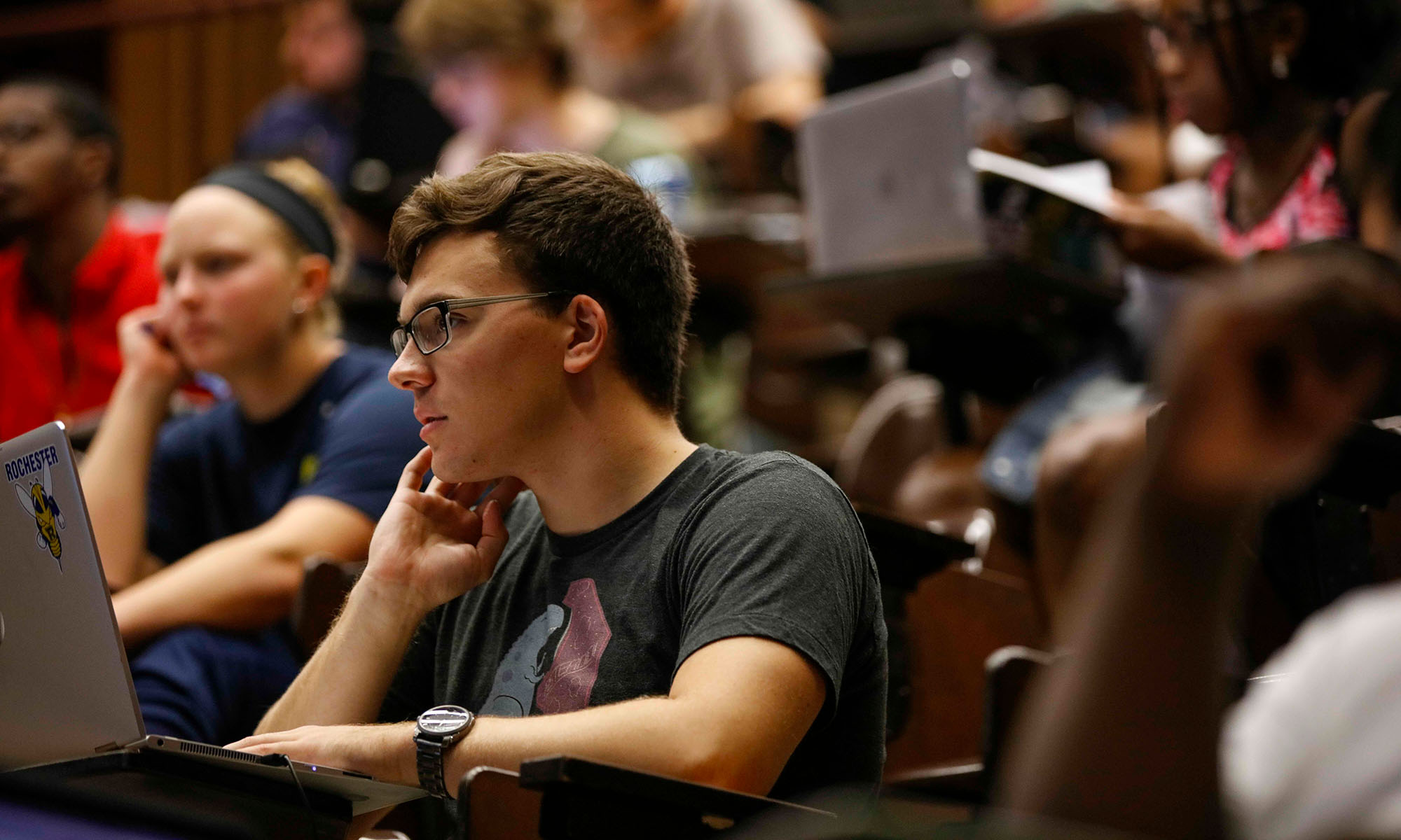 Students with their laptops take in a lecture in a Simon Business School classroom.