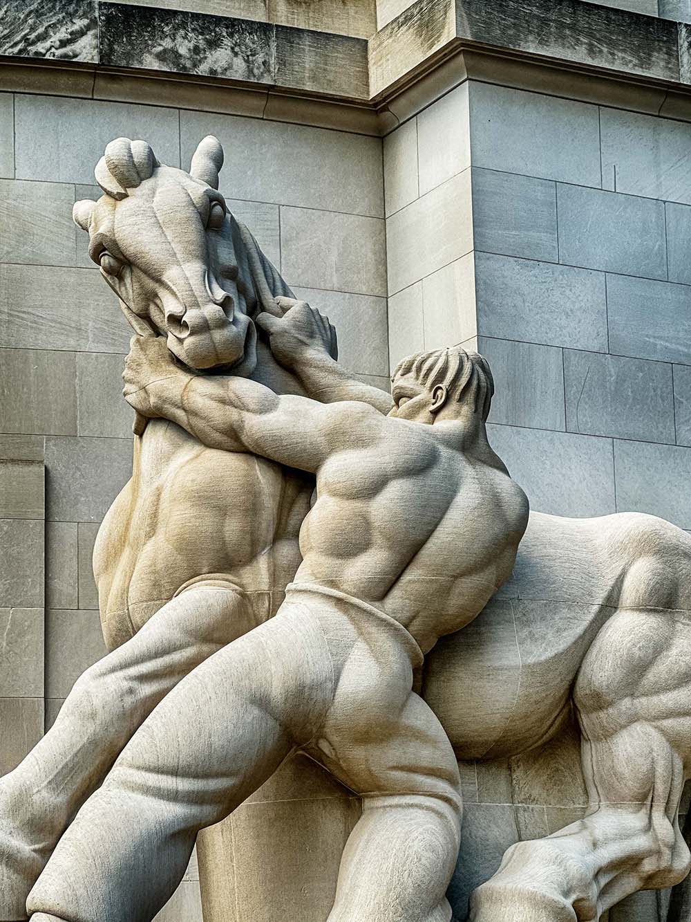 Statue of a strong man holding a horse titled "Man Controlling Trade" in front of the Federal Trade Commission building.