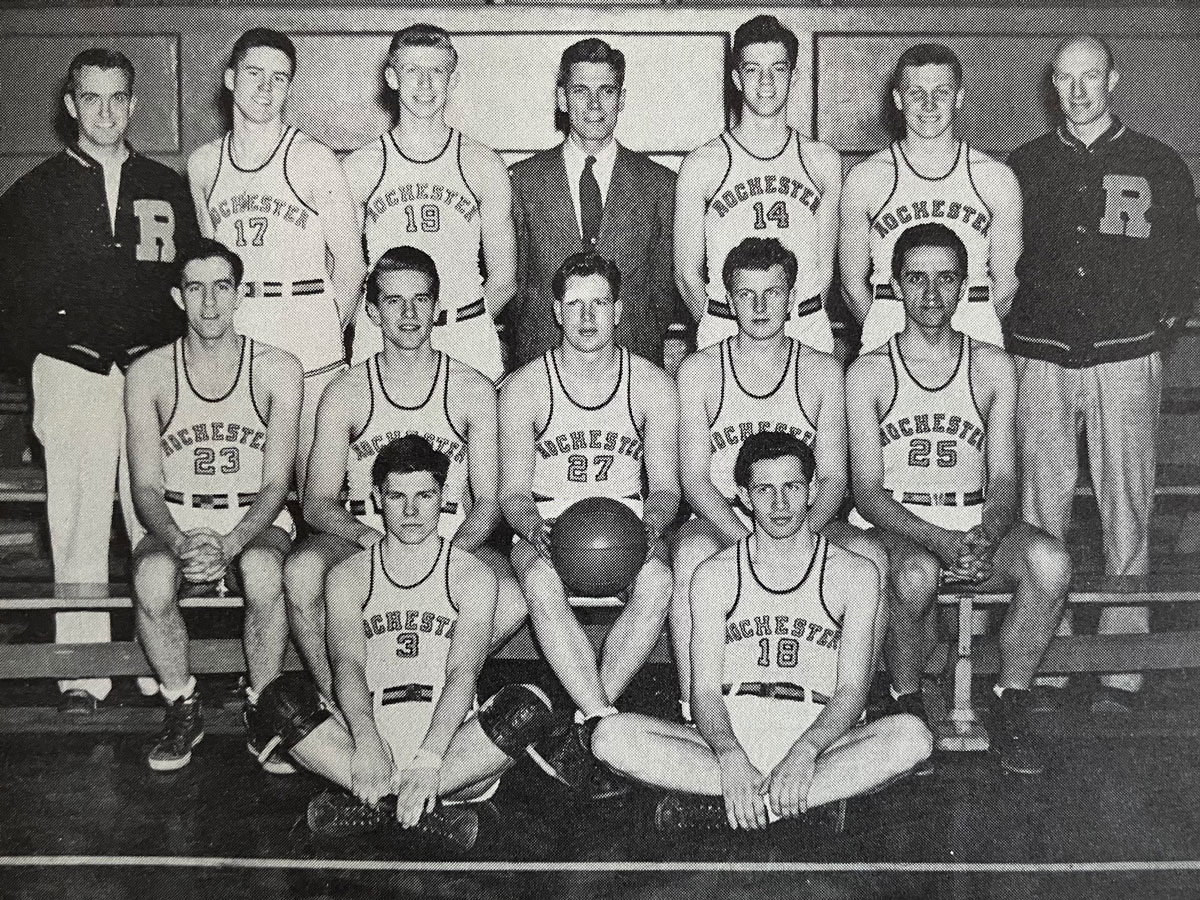 Black and white photo of the University of Rochester basketball team posing together on the court.