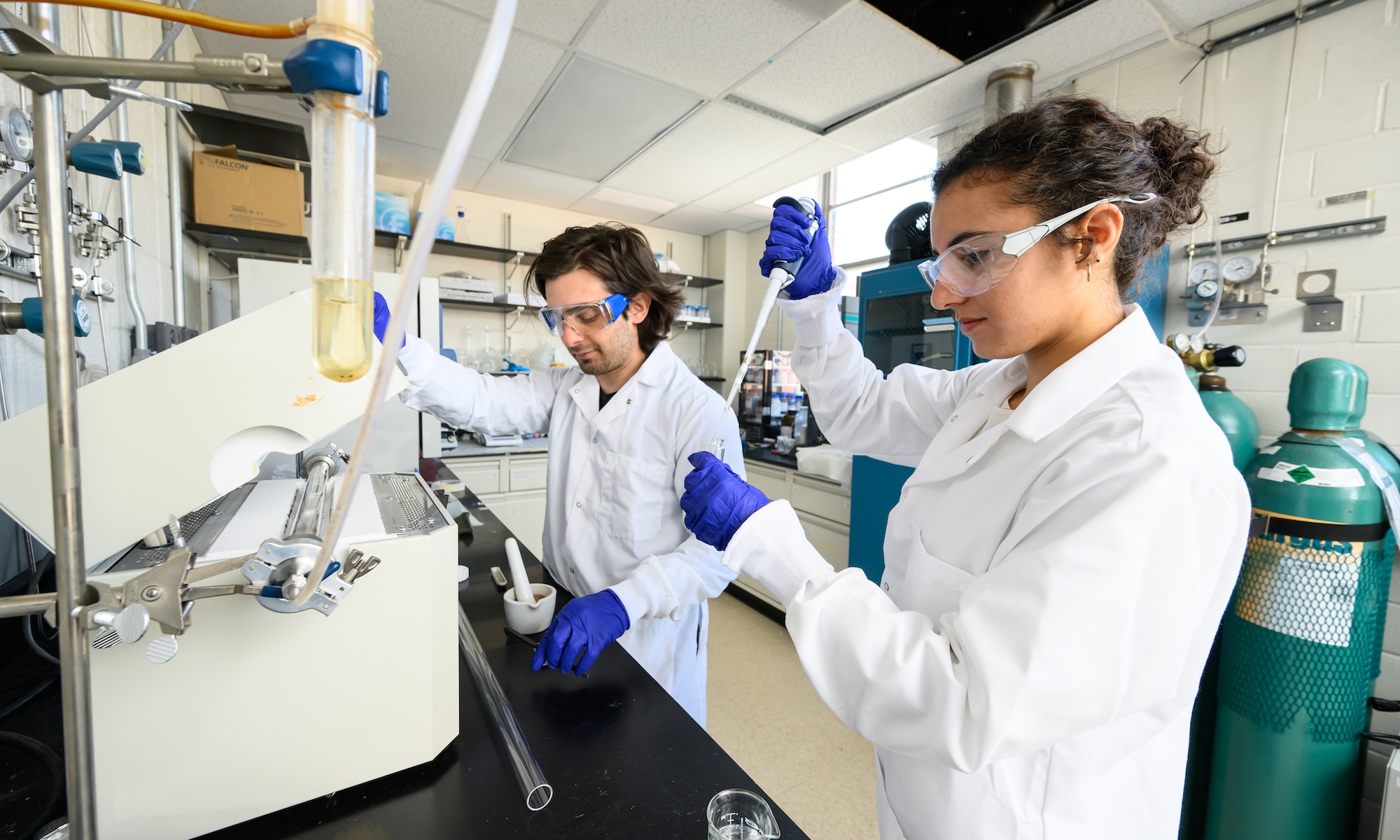 Two scientists in white coats do lab work.