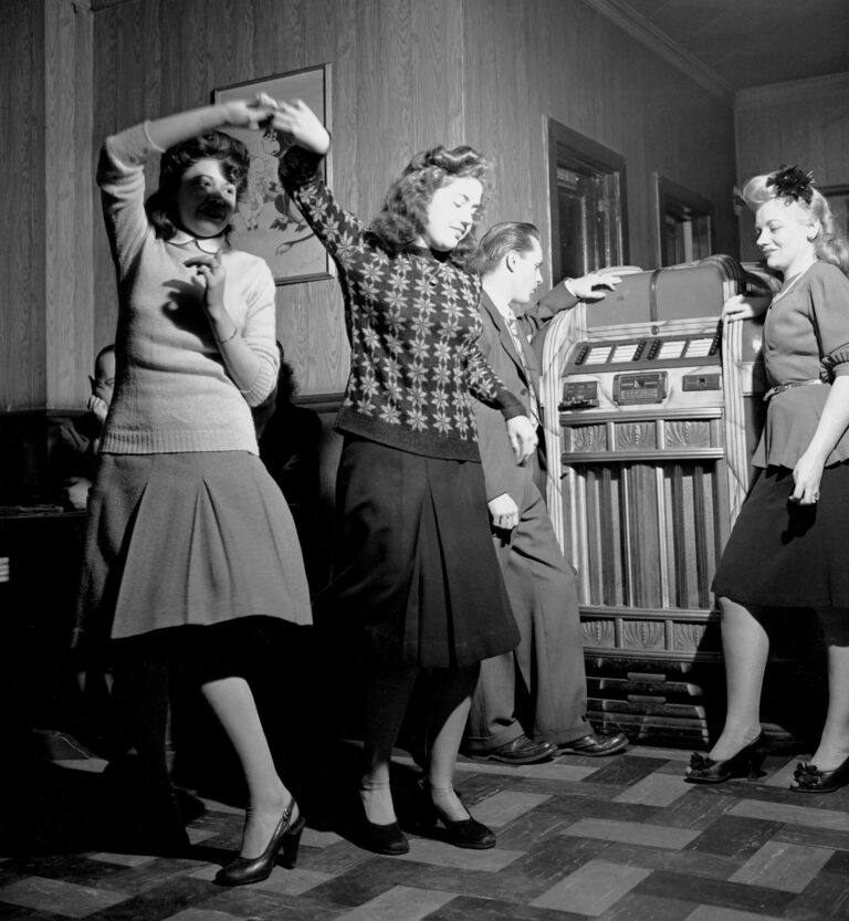 A group of women joyfully dancing in front of a jukebox, enjoying music and each other's company.