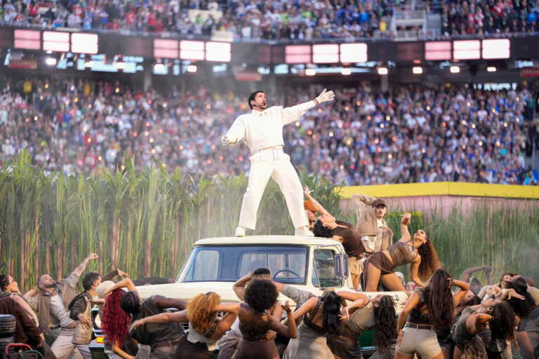 A man stands on a truck, singing to a large crowd of people.