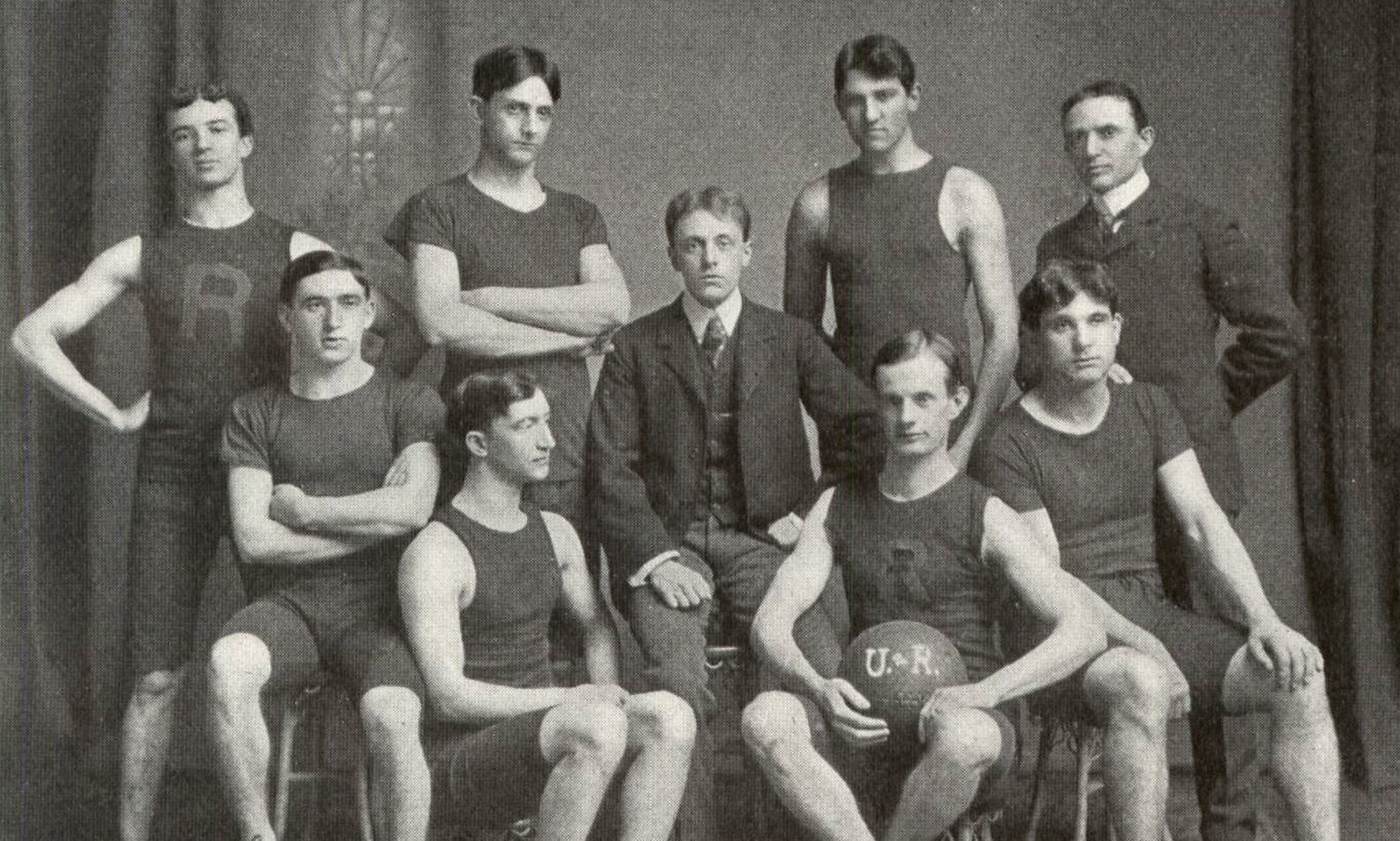 Black and white photo of the University of Rochester basketball team, showcasing players in vintage uniforms.