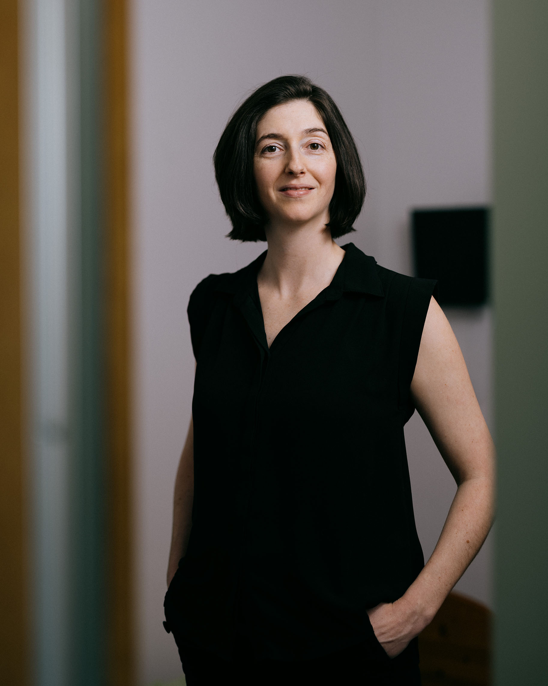 Michelle Carr stands with one hand in her pocket, smiling, photographed in a softly lit interior space.