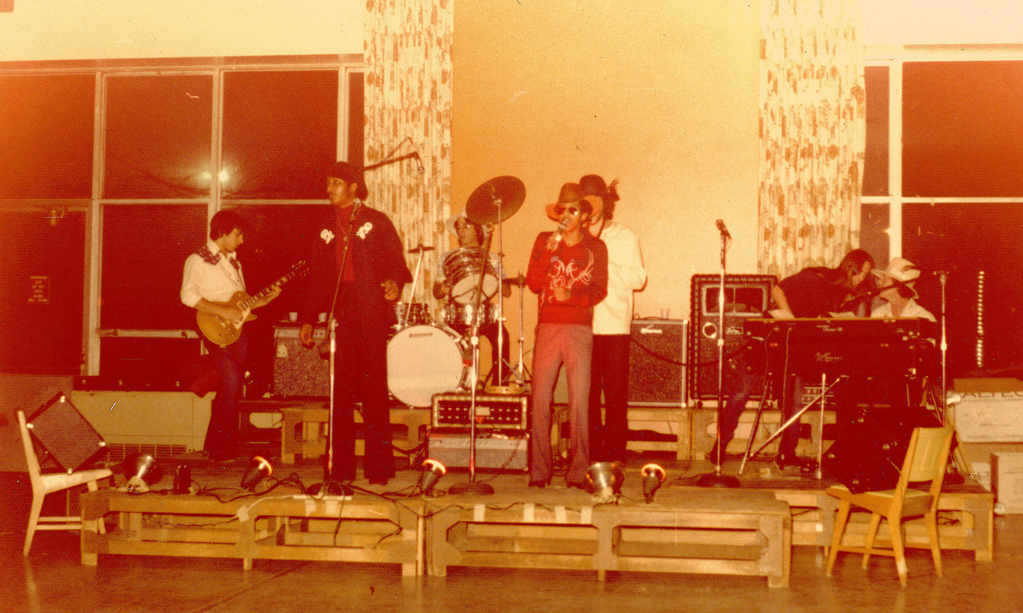 Broad Street Stroke performing on stage at Danforth Dining Center, with members on guitar, drums, keyboard, and vocals.