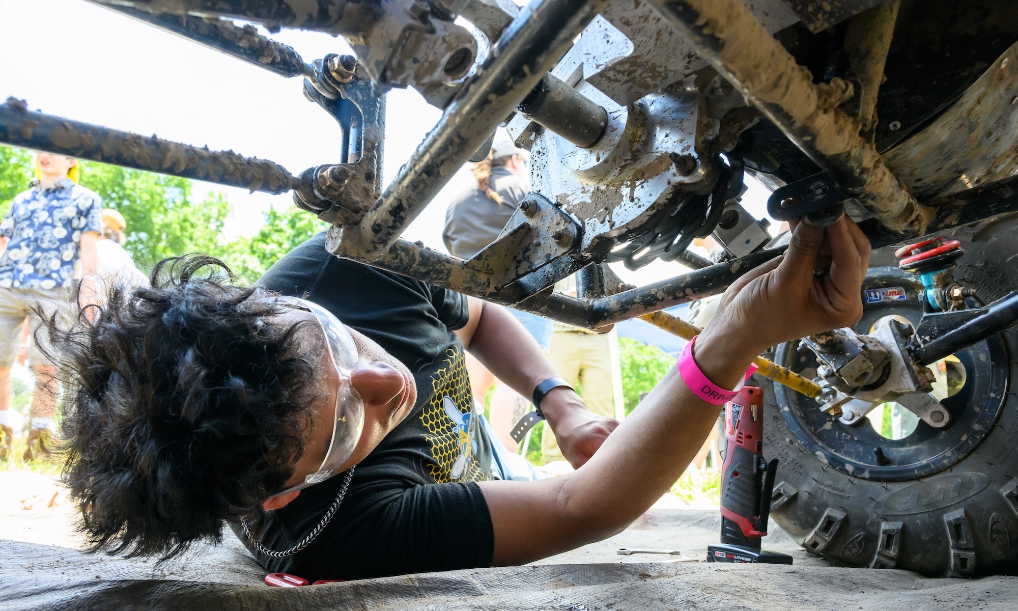 Student works underneath a car on the transmission.