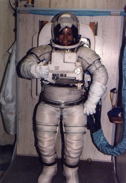 Smiling woman in space suit gives the thumbs-up.