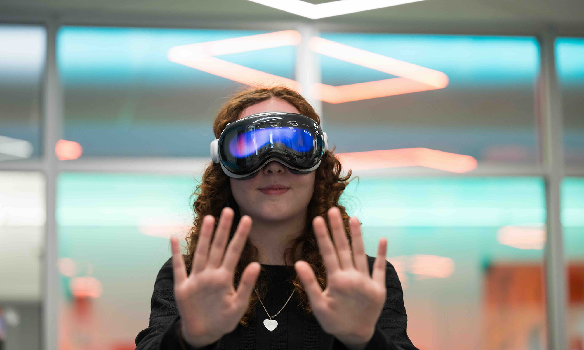 Straight on shot of a URochester student wearing an AR/VR headset with her hands out in front of her.