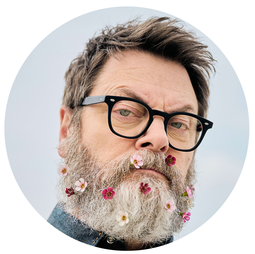Circular crop of Nick Offerman's headshot, complete with flowers in his beard.