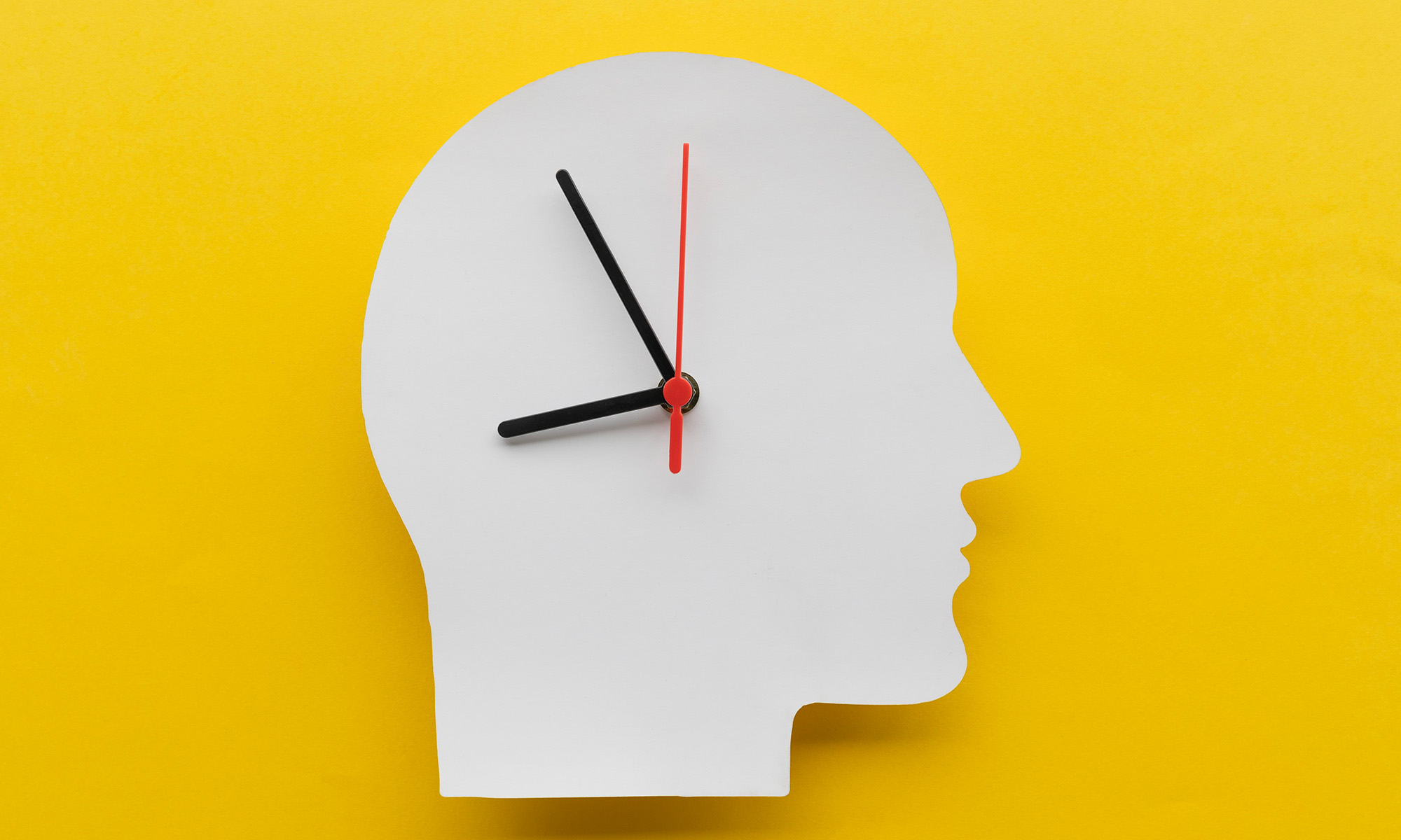 Paper clock in the shape of a head seen in profile.