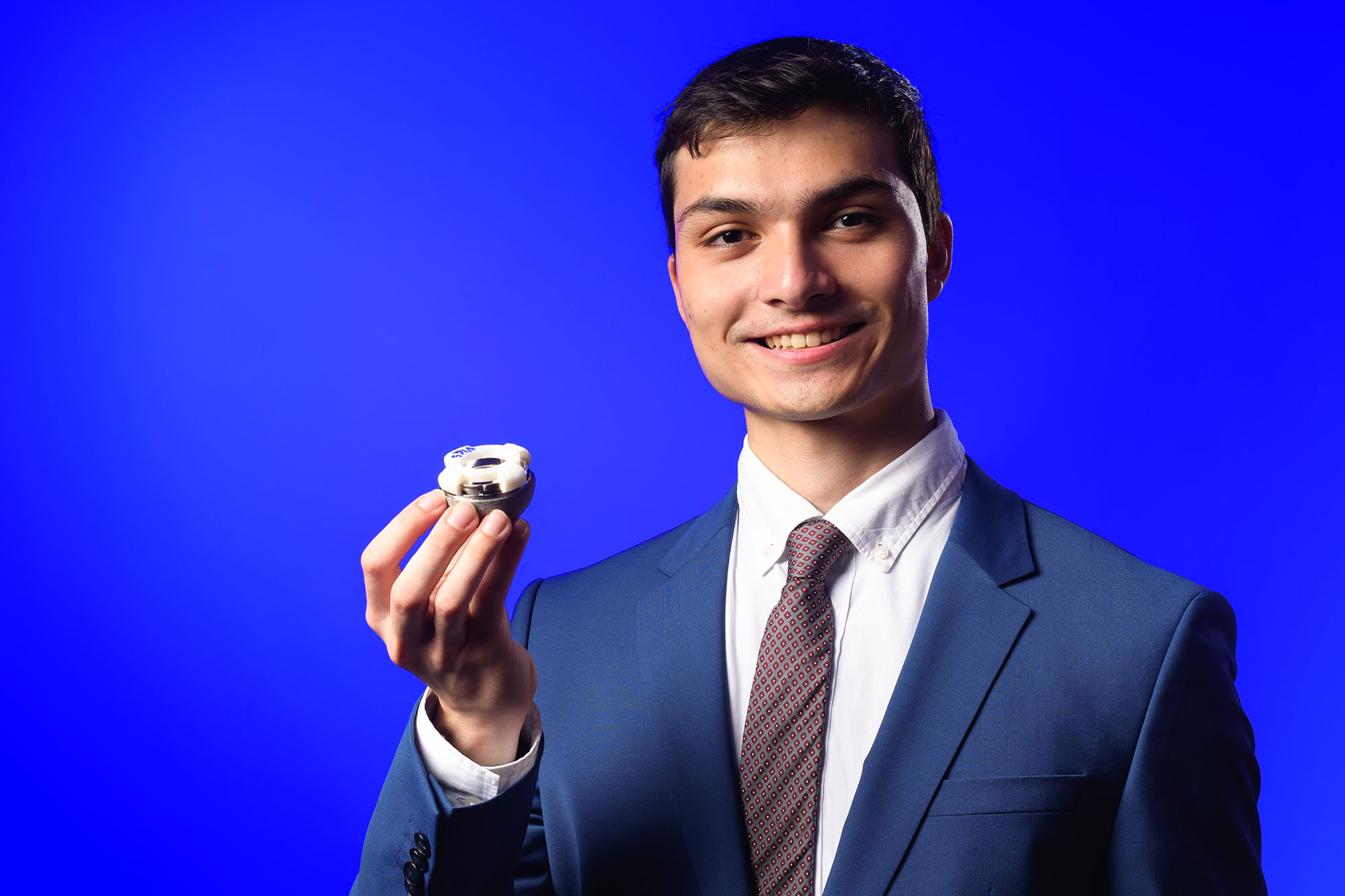 Student entrepreneur Timothy Guida wears a suit and holds his Align-a-Liner invention.