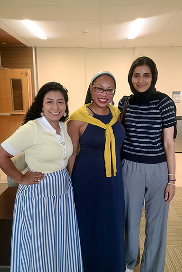 Three Warner School new students pose for a photo inside the atrium of LeChase Hall.